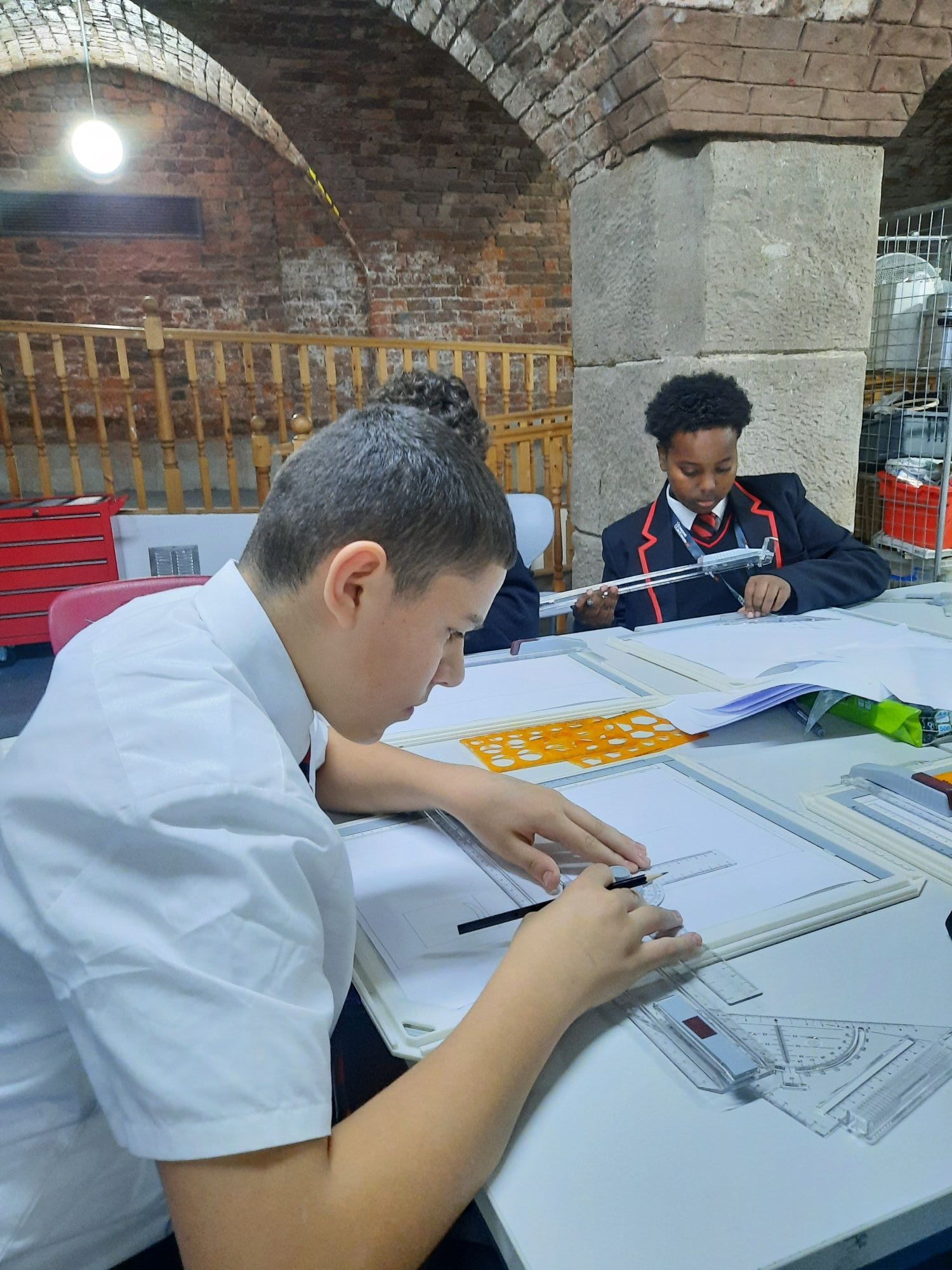 Image of group of students designing ticket machines for a new train station using technical boards in lesson.